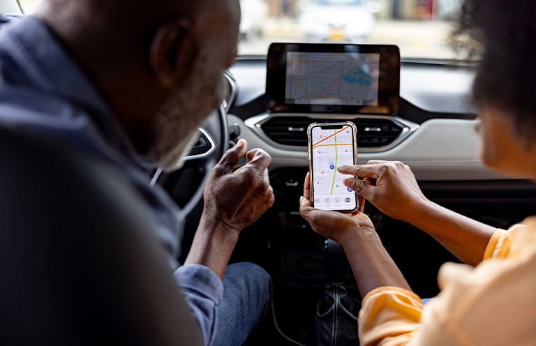 people looking at multiple GPS maps, one on phone and one in car