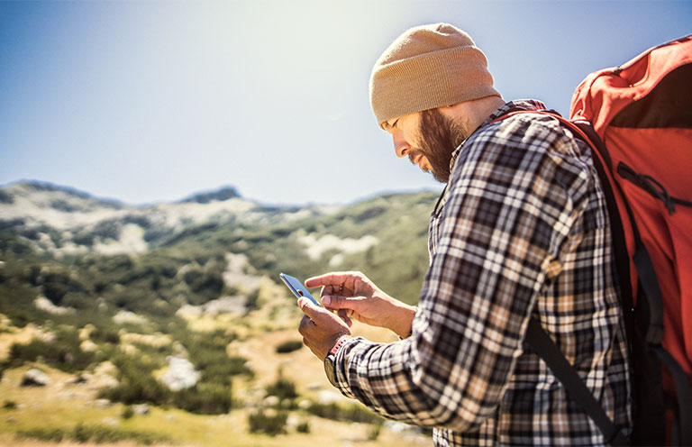 man hiking and looking at navigation app on phone