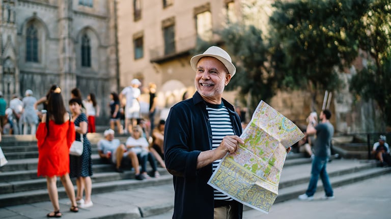 Happy Caucasian man 60s enjoying solo trip vacations for exploring Italy during retirement, cheerful male tourist in straw hat using paper orientation map for walking around historis center. By BullRun