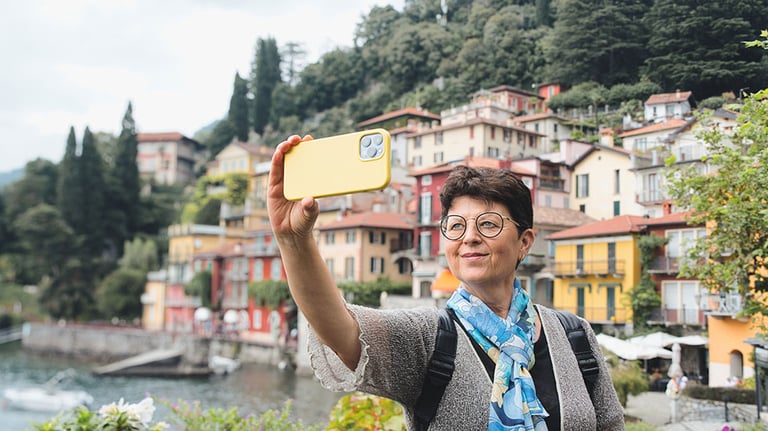 Happy old woman taking selfie with a smart phone in Varenna, Italy. Lake Como city - Older woman enjoying summer holidays - Holidays, mature people and travel concept. By Fotografia Juan Reig