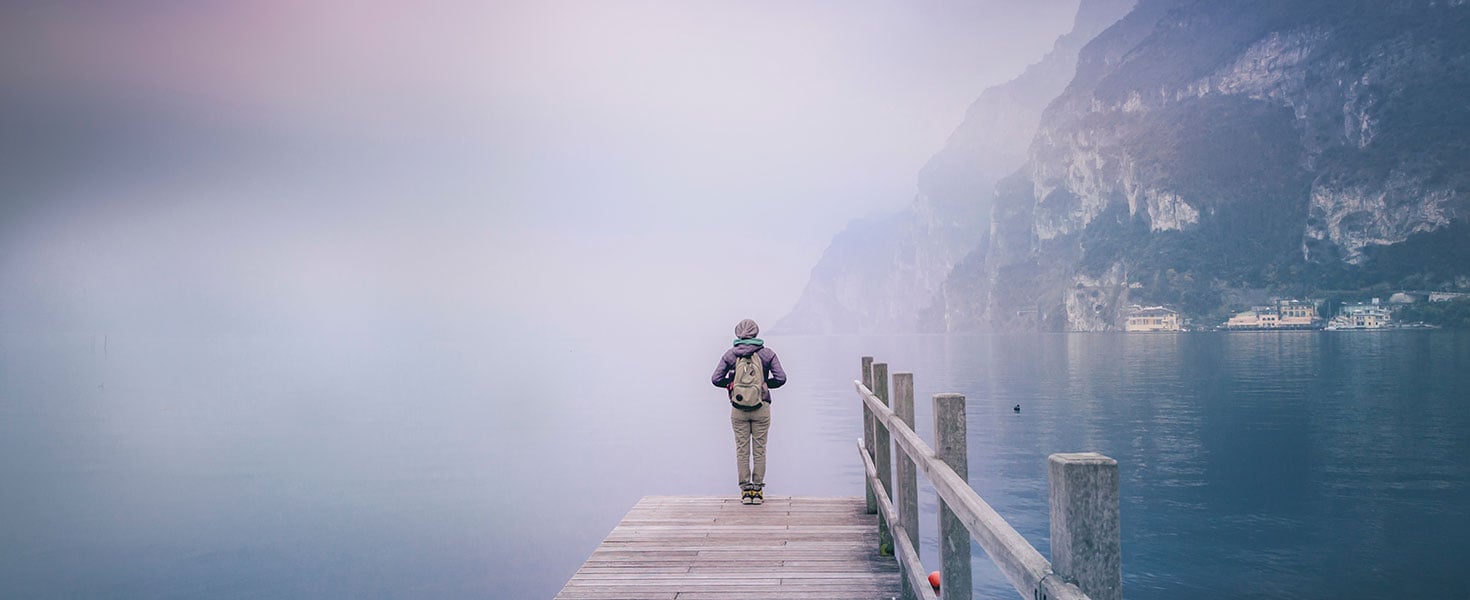 Girl with a backpack on a wooden bridge on Lake Garda, surrounde. By olezzo