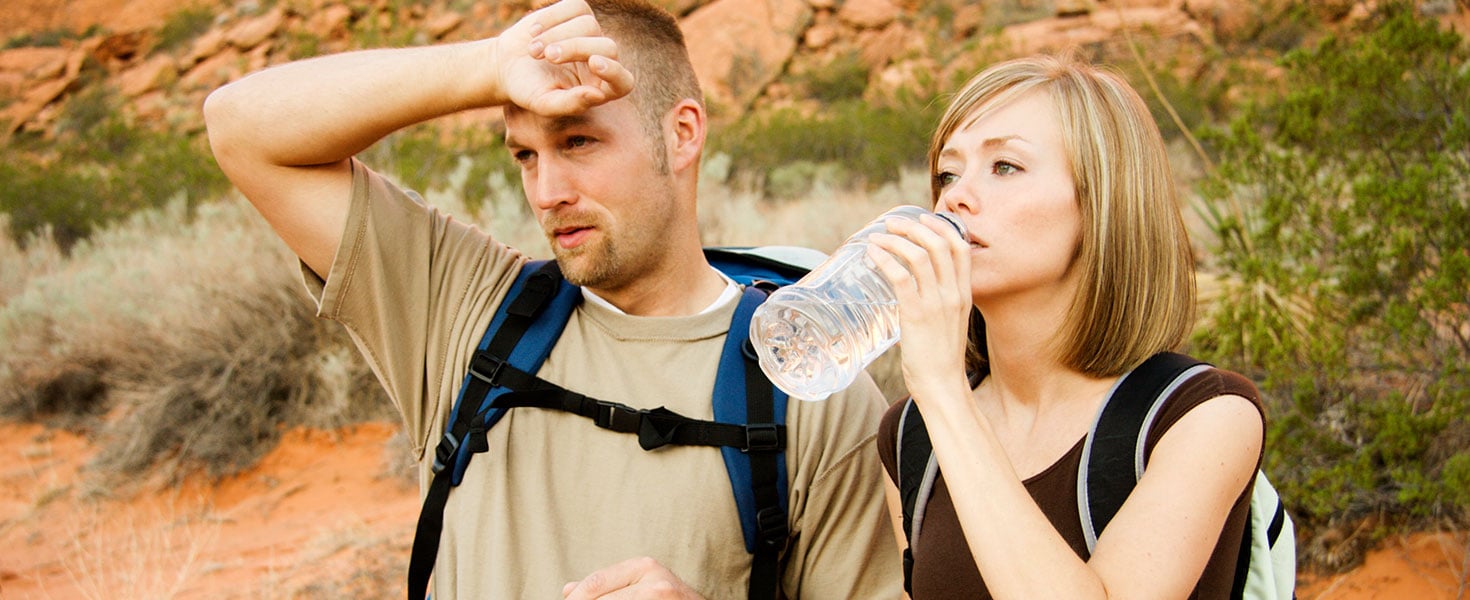 A couple drinks water and wipes sweat on a hot desert hike.Click to see more models- Credit: ReeseImages