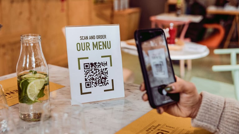 Friends in a restaurant scanning Online Food and Drinks menu. Credit: LeoPatrizi