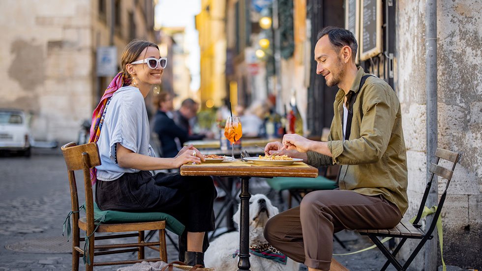 Man and woman eating italian pasta and drinking wine at restaurant on the street in Rome. Concept of Italian gastronomy and travel. Italian couple having lunch together. Credit: RossHelen