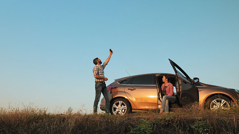 Man and woman traveling by car catches a phone signal while standing on the side of the road  by DiedovStock