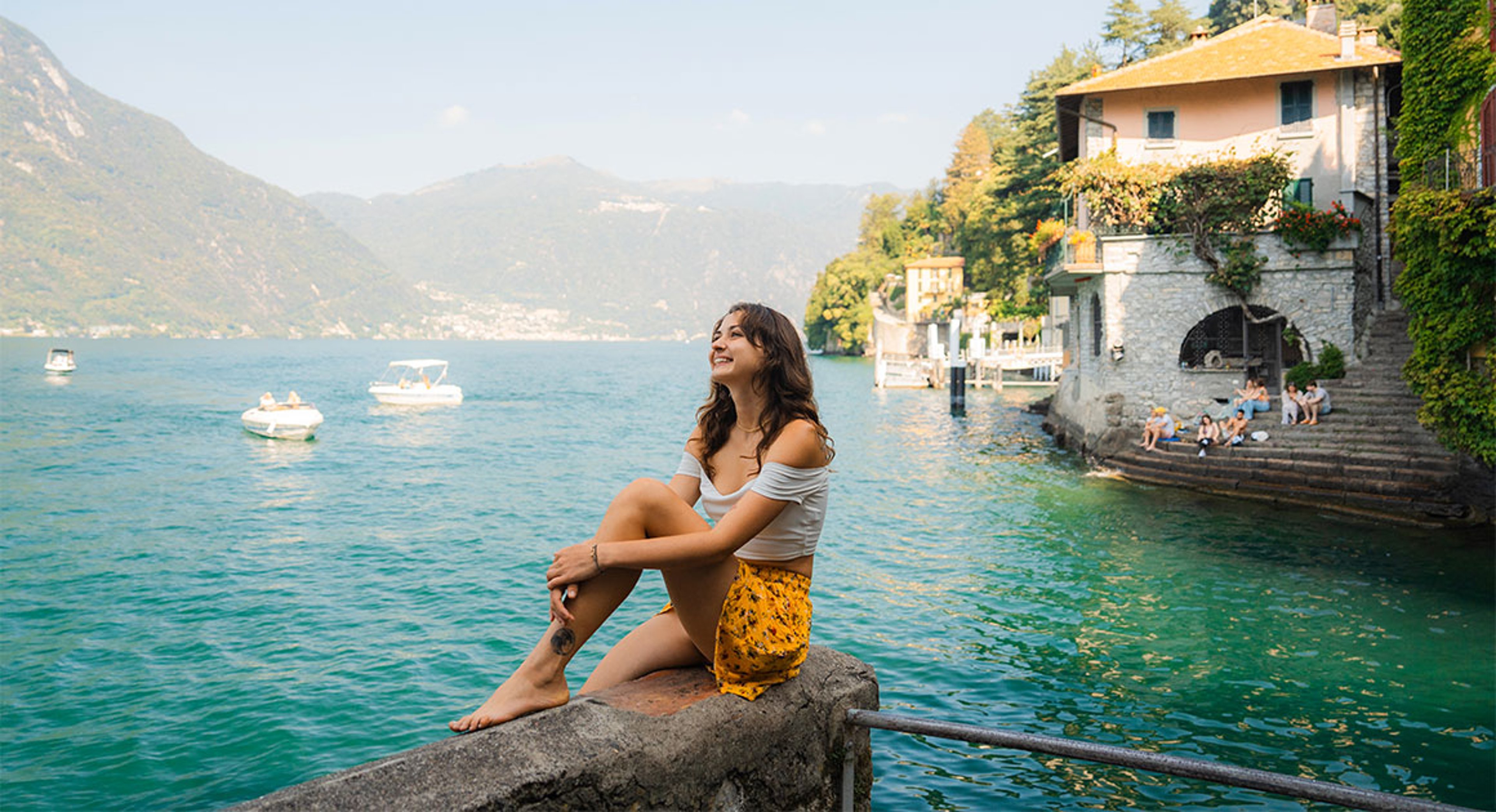 girl sitting on ledge by lake in Italy
