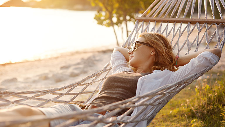 beautiful girl in a hammock on the beach, watching the sunset By olezzo