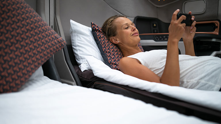 Pretty, young woman abord a first class commercial flight using their cell phone during flight; By lightpoet