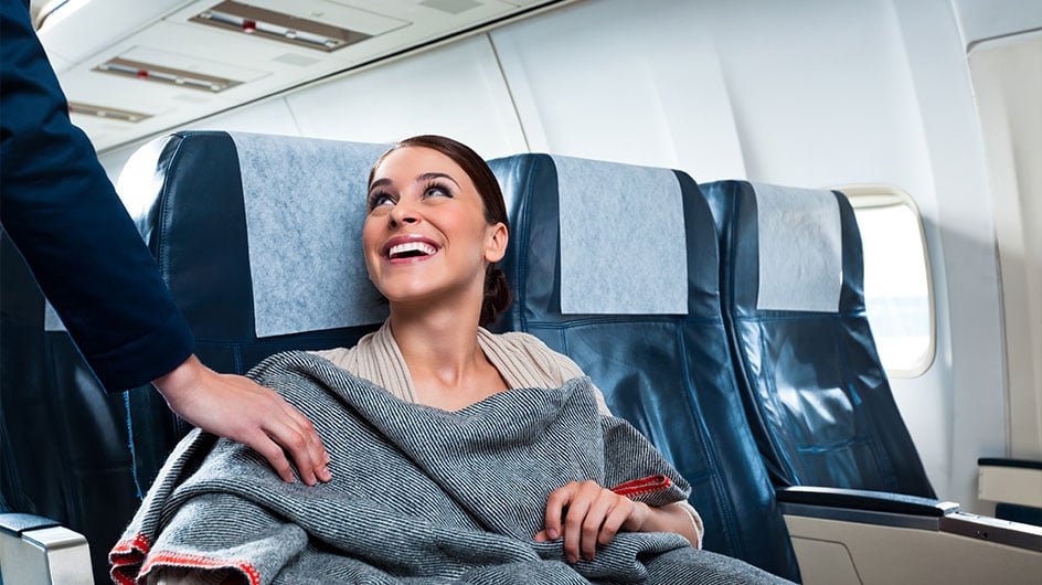 woman sitting on plane wearing blanket