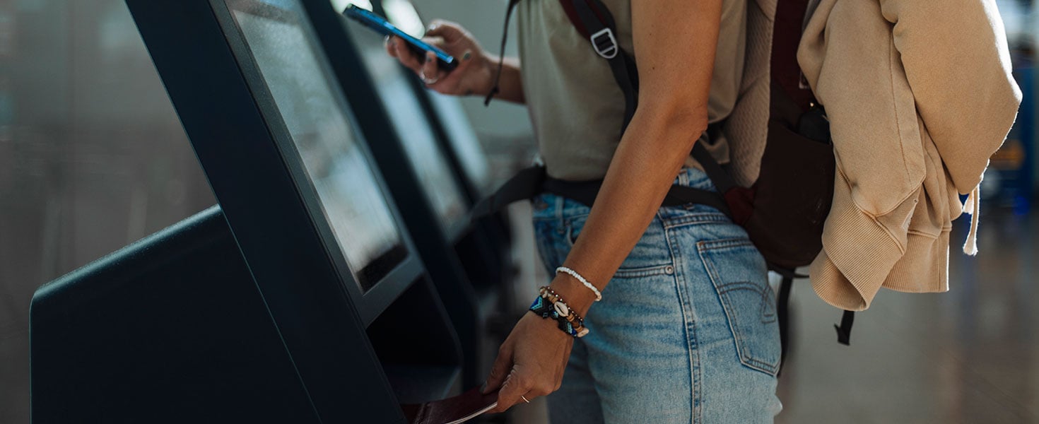 Young woman goes through self-check-in at the airport for her flight Credit: mihailomilovanovic