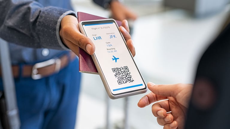 Close up hand of mixed race man showing electronic boarding pass to flight attendant on phone. Hostess checking electronic flight ticket at boarding gate. Airport check in counter and online air ticket. Credit: Ridofranz