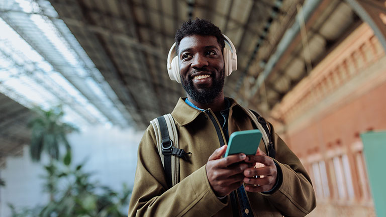 Tourist listening to music on his smart phone in a train station By bernardbodo