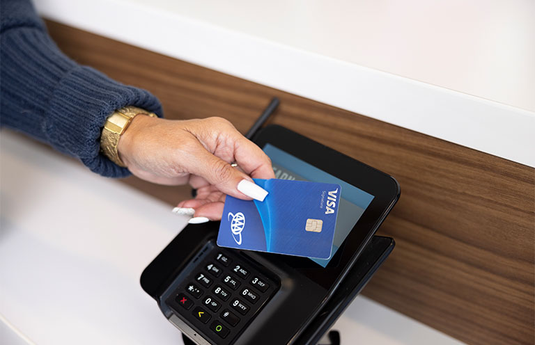 woman using aaa visa card at a card reader checkout