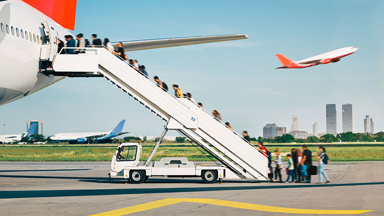 People are boarding from apron, by the stairs. Background city view. by Yaar