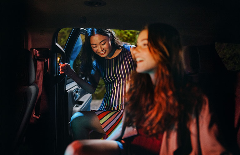 girl getting in backset of car to join other passengers