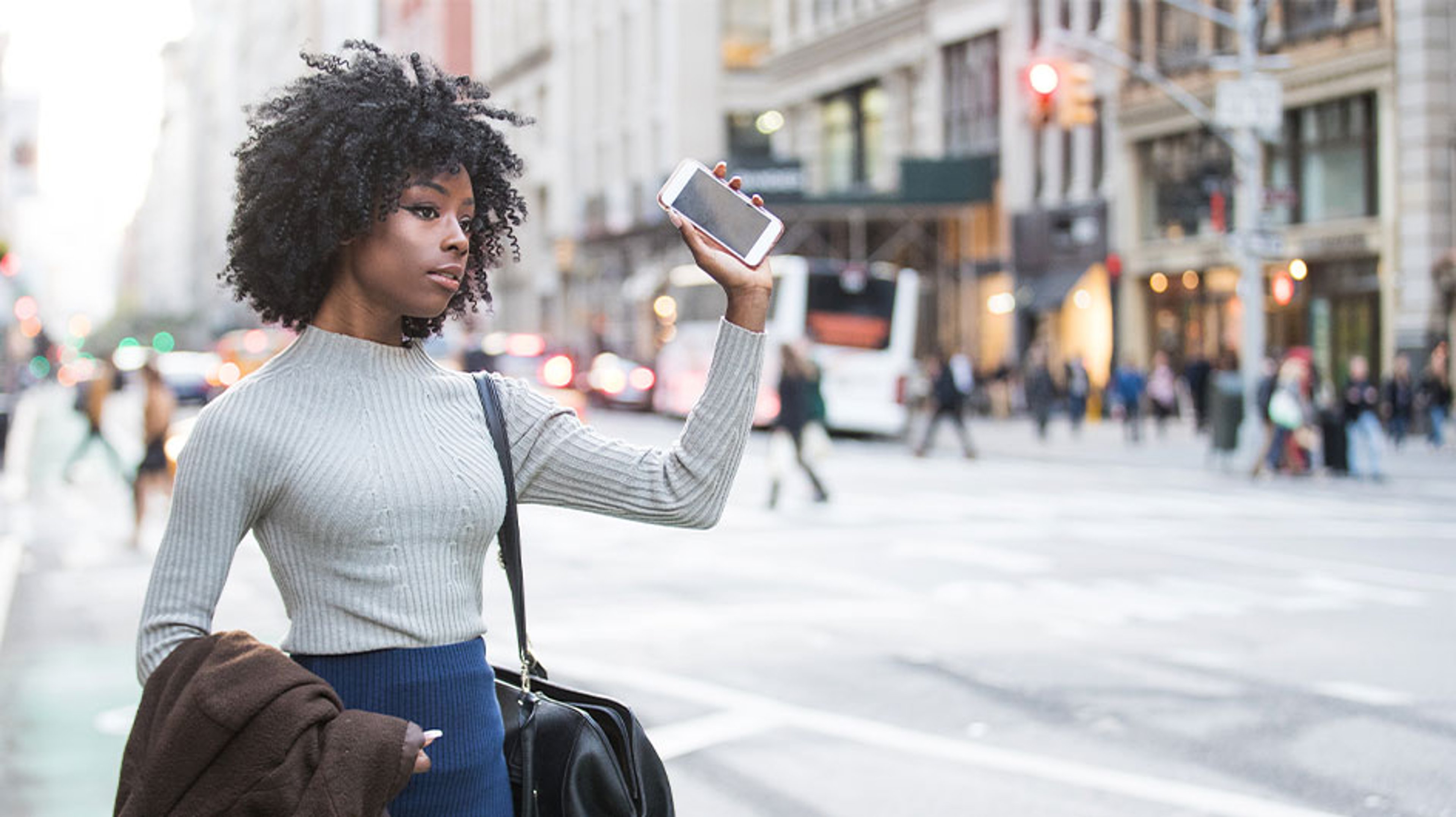 woman waiting for ride on side of populated street