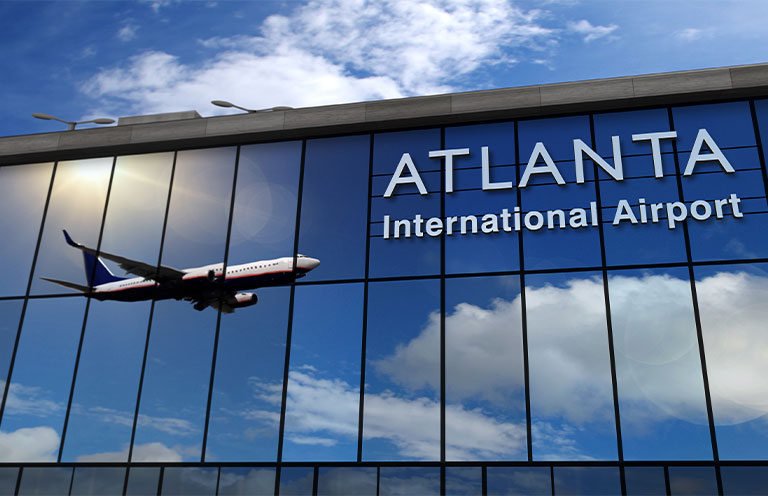 reflection of plane flying in sky shown on windows of Atlanta International Airport
