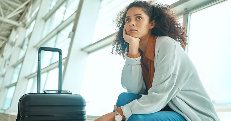 woman sitting with suitcase at airport, waiting for flight