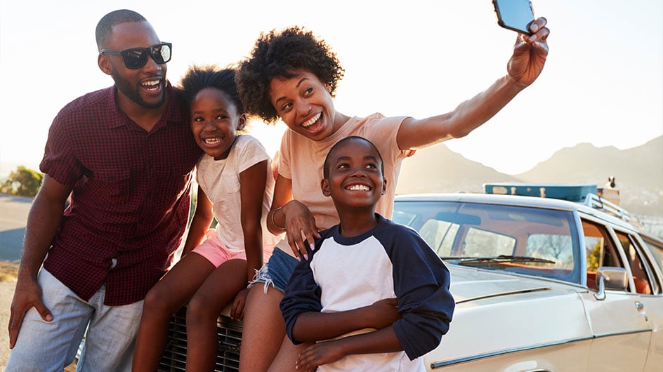 family taking photo on hood of car