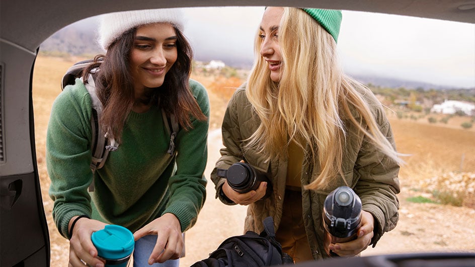 two women putting supplies into car trunk
