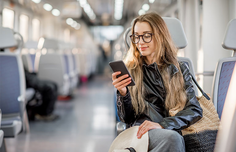 woman sitting on train using phone