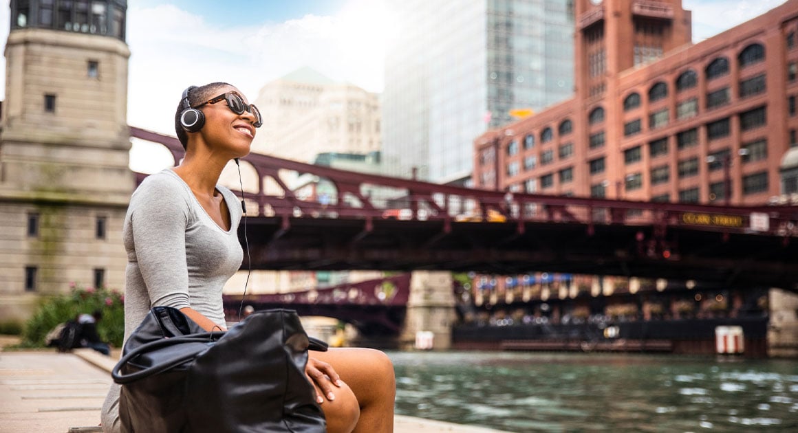 woman sitting by water listening to music