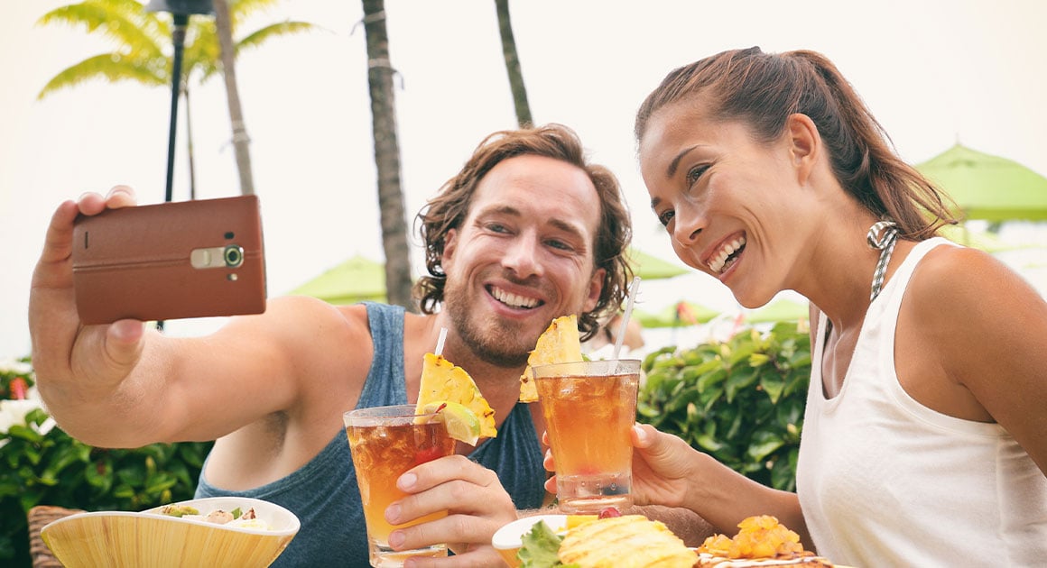 man and woman taking selfie in a tropical setting