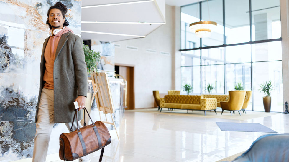 man walking across hotel lobby with duffle bag