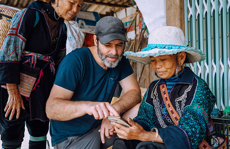 male tourist showing mobile phone to indigenous woman in Vietnam