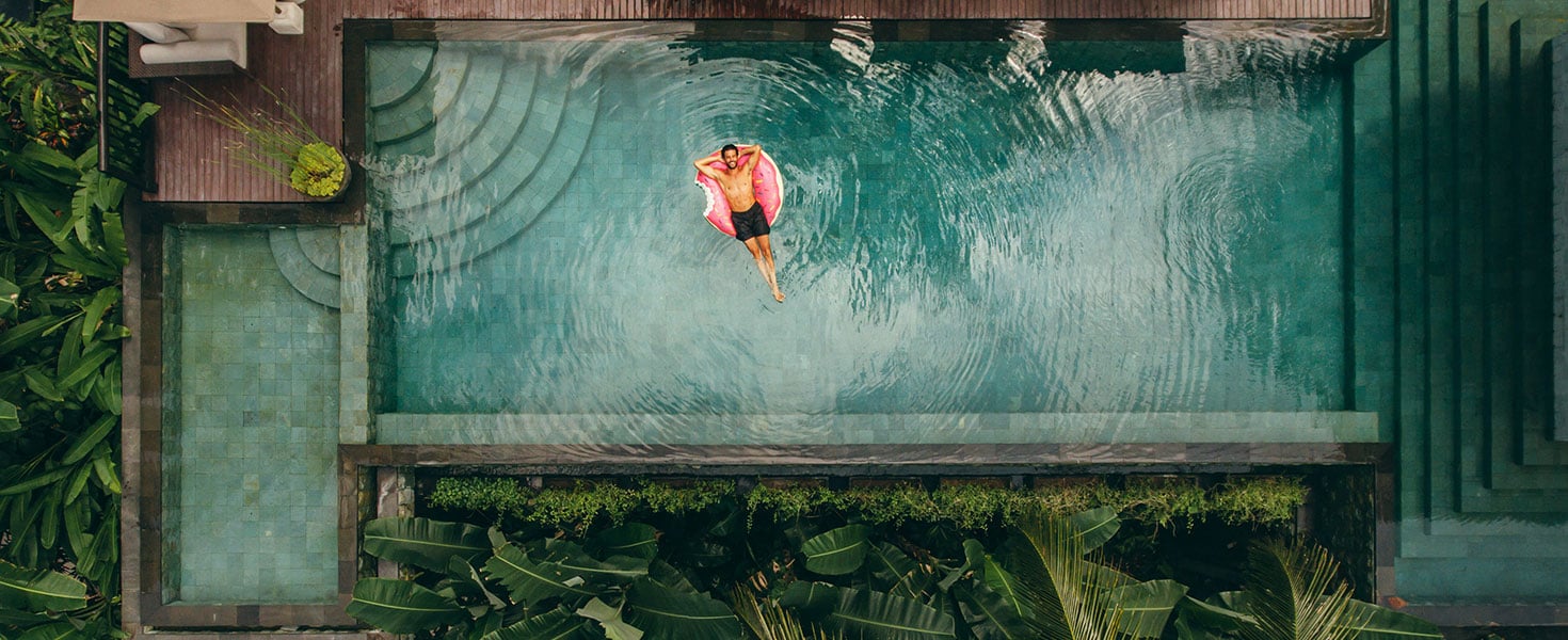 Young man relaxing in resort swimming pool By Jacob Lund