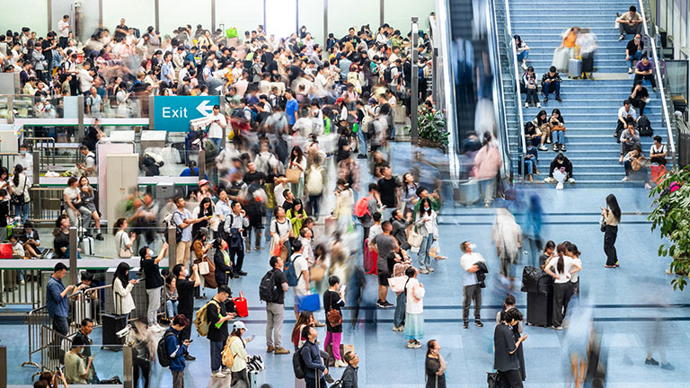 Crowd of passengers walking at railroad station stock photo; Credit: baona 