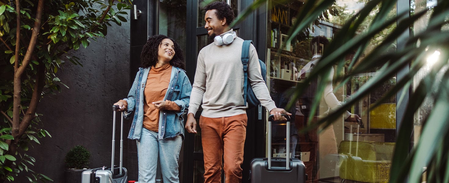 man and woman with suitcases outside hotel