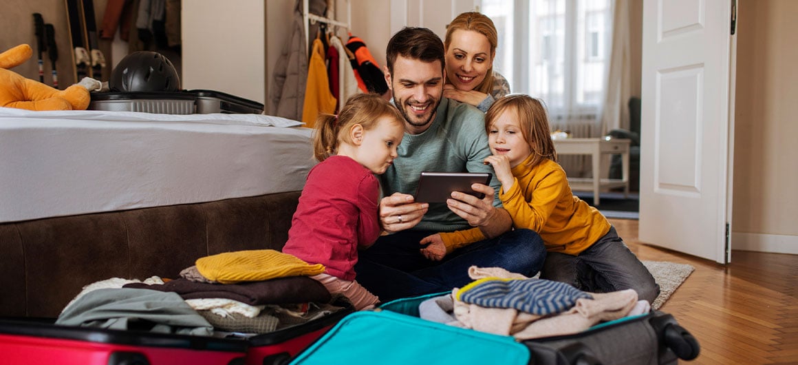 family packing suitcases and looking at phone