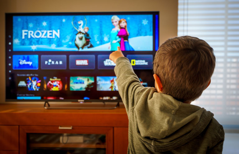 Kid pointing at tv showing Frozen banner on Disney Plus