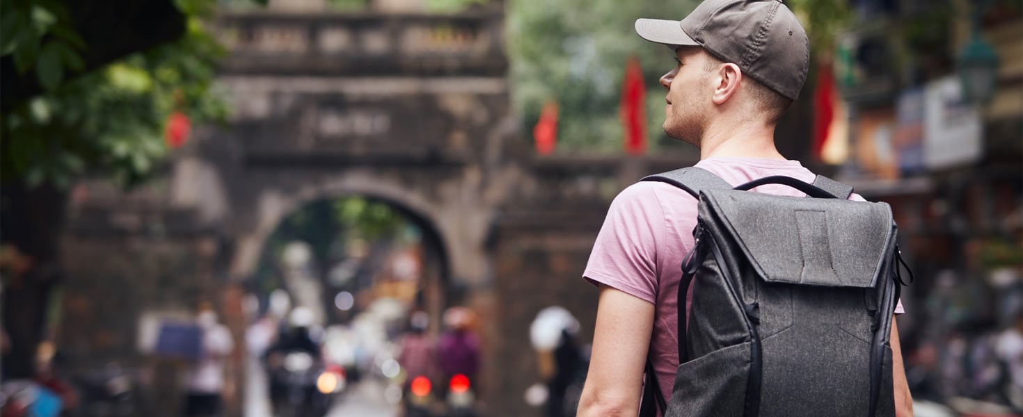 Man with baseball cap and back pack looking away from camera