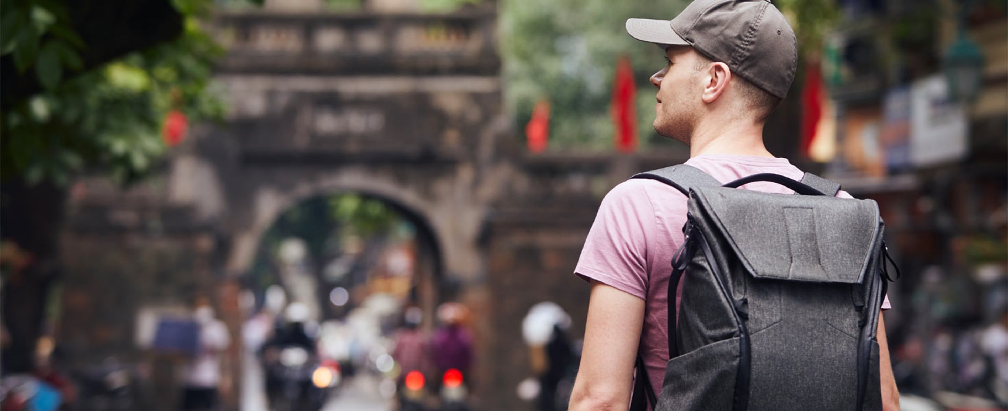 Man with baseball cap and back pack looking away from camera