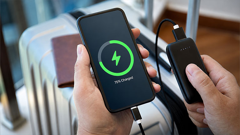 man hands holding phone with isolated screen and powerbank suitcase airport lounge; Credit: Prykhodov