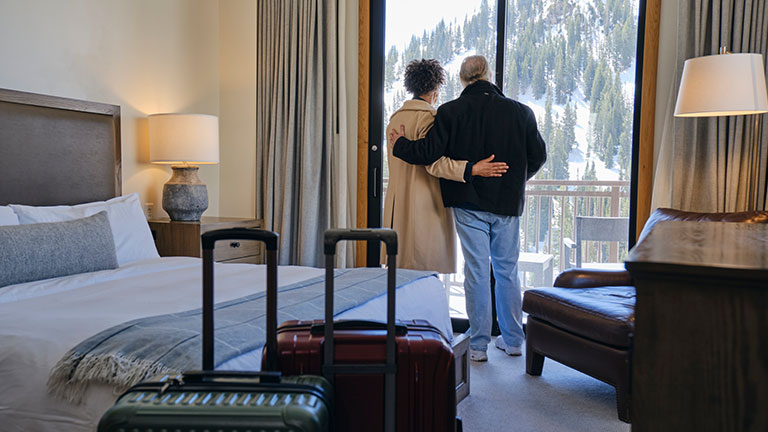 A senior aged couple entering their hotel room and enjoying the view at a ski resort. Credit:O2O Creative
