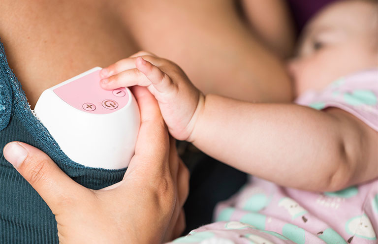 mom breastfeeding baby while wearing wearable electric breast pump
