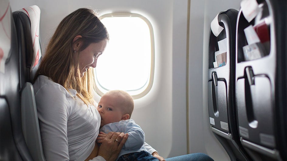 woman breastfeeding baby on plane