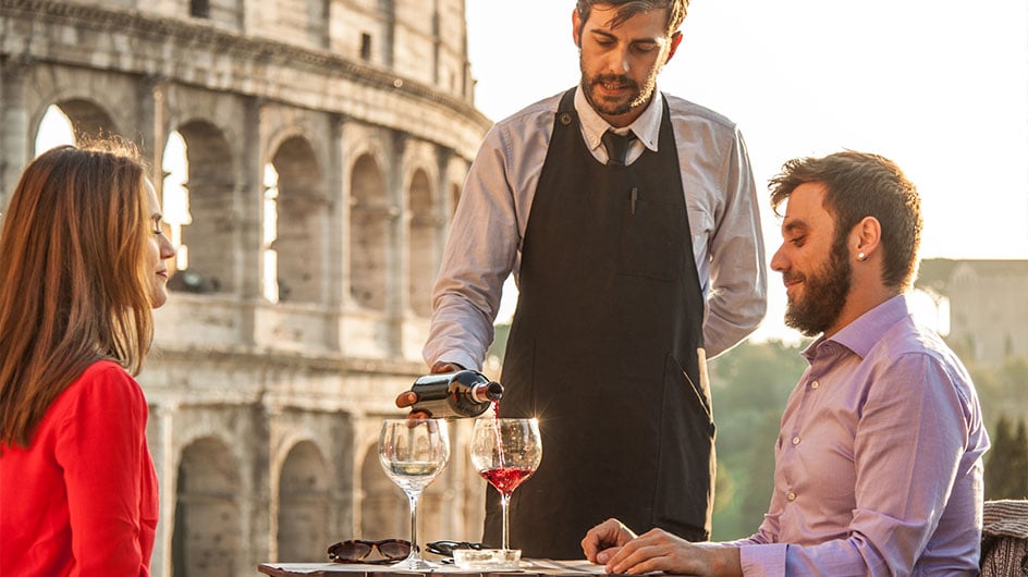 man and woman having wine in front of Roman colosseum