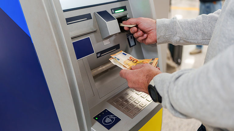 Traveler pulling euros from airport ATM, preparing financial resources for international journey by Javier