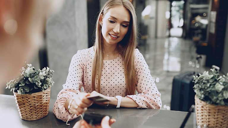 Young beautiful woman hotel guest paying for her stay with credit card at front desk by fotofabrika