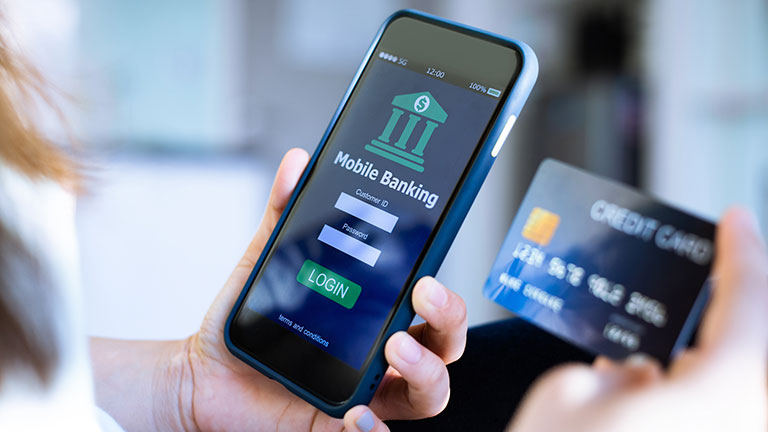 Mobile online banking concept.Close-up of Female hands using mobile phone and holding credit card by panuwat