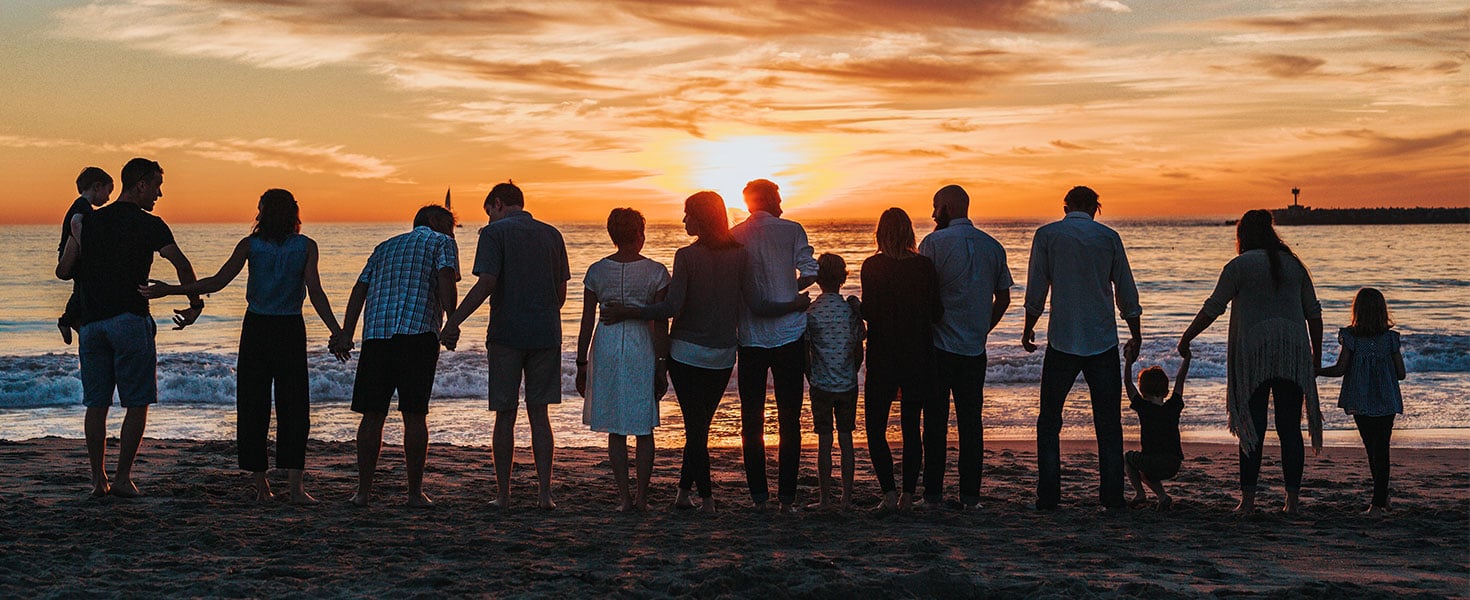 family facing sunset on beach