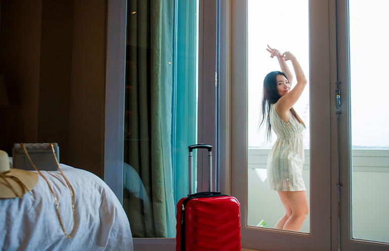 lifestyle portrait of young happy and beautiful Asian Korean tourist woman arriving to luxury hotel room dancing on balcony staring around delighted