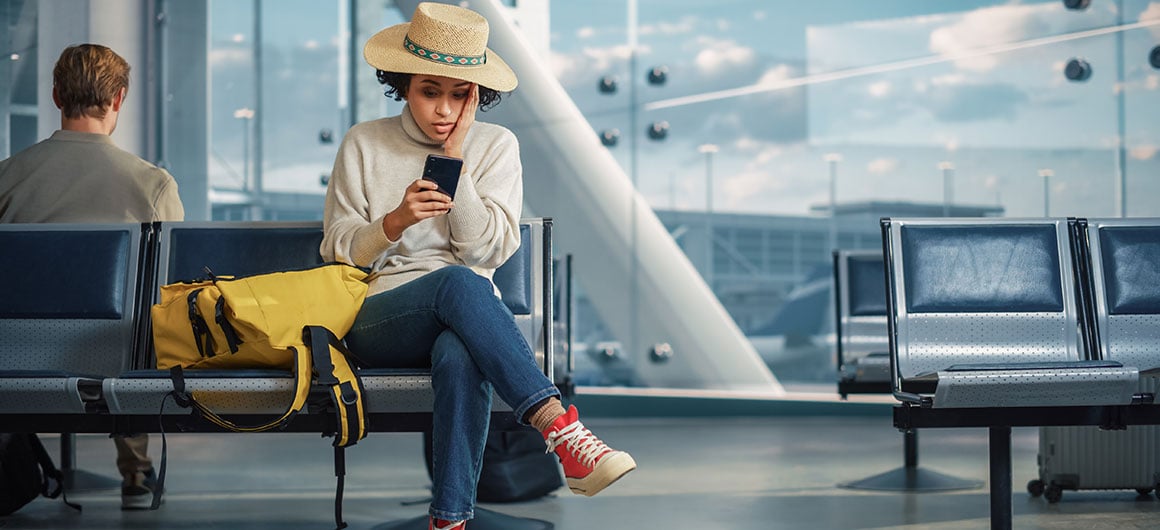 Airport Terminal: Black Woman Waits for Flight, Uses Smartphone, Receives Shockingly Bad News, Misses Flight. Upset, Sad, and Dissappointed Person Sitting in a Boarding Lounge of Airline Hub. stock photo
