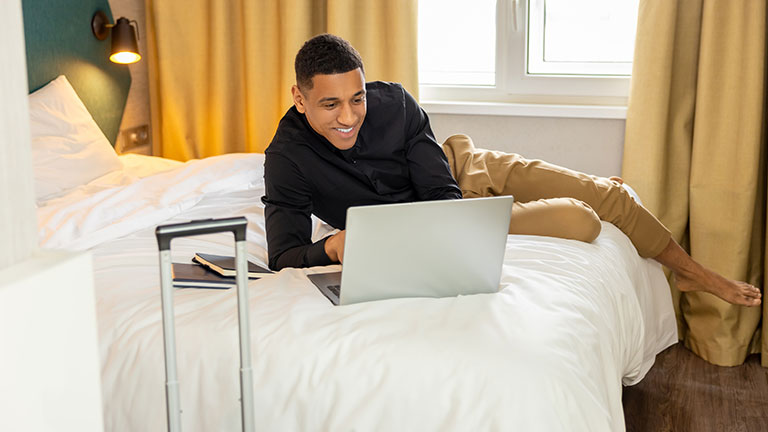 Smiling young man chatting online and feeling good; Credit: Zinkevych