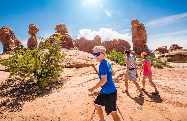 A happy family hiking together in the beautiful rock formations of Arches National Park.