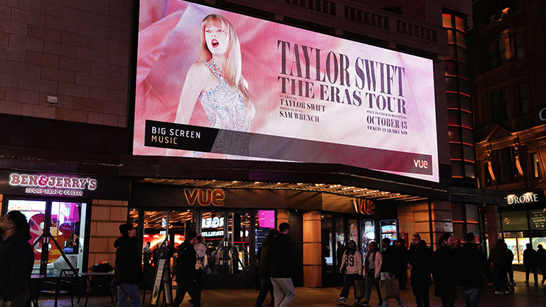 On October 15th, 2023, in the photo capturing the Vue West End building in London's West End, the bustling Leicester Square became a focal point, attracting a multitude of visitors engaged in various activities. Both tourists and local British individuals contribute to the lively atmosphere as they fill the square, immersing themselves in the vibrant surroundings. Some individuals are observed leisurely strolling, embracing the energetic ambience, while others pause to capture moments through photographs. The facade of the Vue West End building prominently displays advertisements for the movie "Taylor Swift: The Eras Tour," a music/musical and concert movie released in 2023. As a highly popular tourist area, Leicester Square in the City of London, England, continues to draw significant attention from both domestic and international visitors, seeking entertainment and cultural experiences.